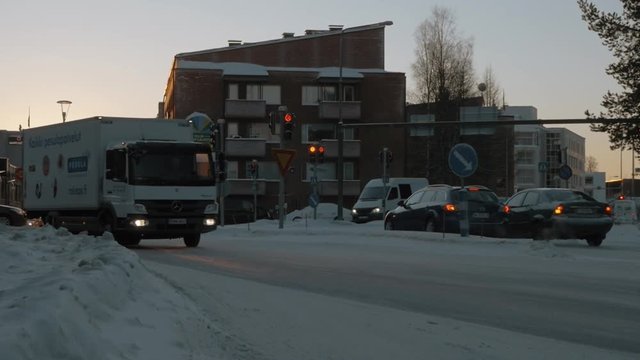 ROVANIEMI, FINLAND - JANUARY 06, 2017: Slow motion shot or cars driving in snowy streets of the city at sunset. Warm light of evening golden sun