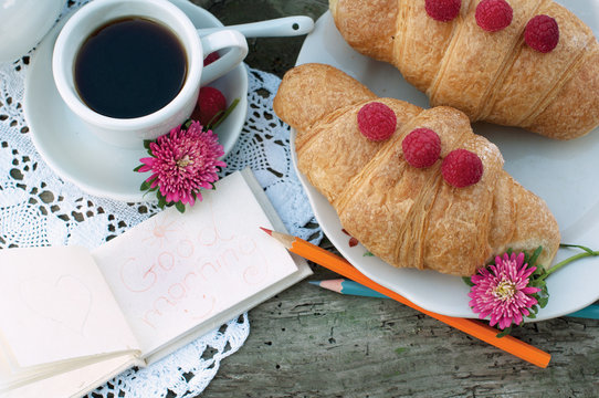 Breakfast with cup of coffee. A dessert with croissants and berries of raspberry on white a lace tablecloth