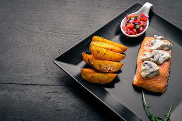 Baked salmon with mushroom sauce and potatoes. On a wooden background. Top view. Free space.