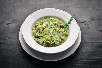 Risotto with spinach, cheese and olives. On a wooden background. Top view. Free space.
