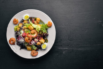 Salad of vegetables and shrimp and quail eggs. On a wooden background. Top view. Free space.