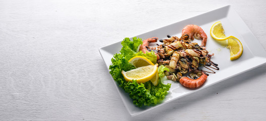 Cold snacks. Seafood, shrimp, mussels, squid, octopus. On a wooden background. Top view. Free space.