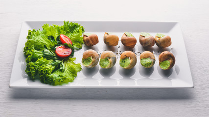 French and Italian cuisine. Baked snails. On a wooden background. Top view. Free space.