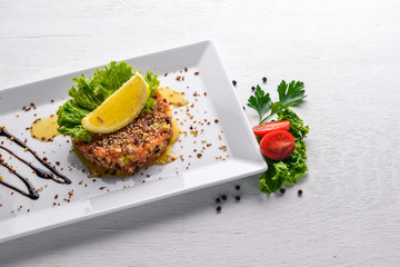Salted salmon and fresh vegetables with balsamic sauce in a plate. On a wooden background. Top view. Free space.