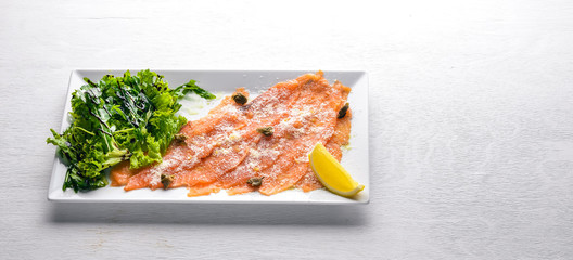 Carpaccio of salmon. On a wooden background. Top view. Free space.