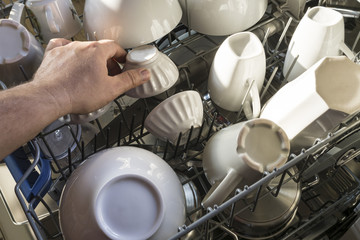 Close Up Of Man Loading Crockery Into Dishwasher