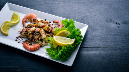 Cold snacks. Seafood, shrimp, mussels, squid, octopus. On a wooden background. Top view. Free space.