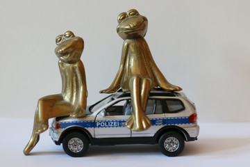 Frogs in Love sitting on top of a toy police car.