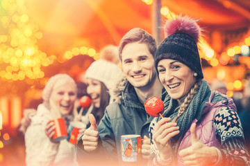Friends drinking mulled wine and eating crystalized appels on German Christmas Market