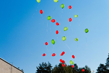 Balloons. The children released a lot of balls with ropes in the sky.Red  and green balloons in the blue sky in the rays of the sun. Selective focus.