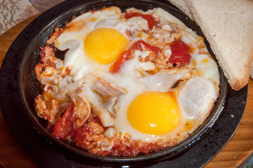 Fried eggs with tomatoes .