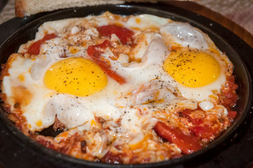 Fried eggs with tomatoes .