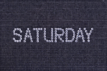 Day of the week, word SATURDAY is made rhinestones crystal color on a black canvas background.