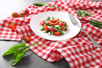 Plate with strawberry spinach salad on napkin