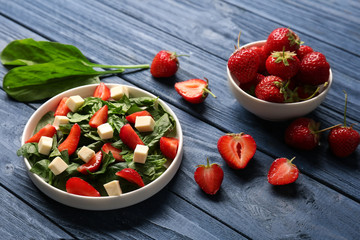 Plate with strawberry spinach salad on wooden table