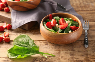Bowl with strawberry spinach salad on wooden table
