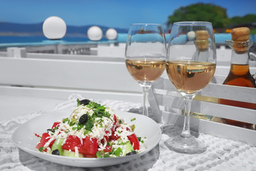Two glasses of white wine and plate with exotic salad on table outdoors