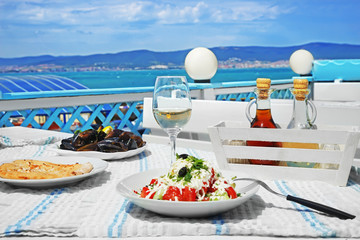 Plates with exotic salad, flatbread and mussels on table in open air restaurant