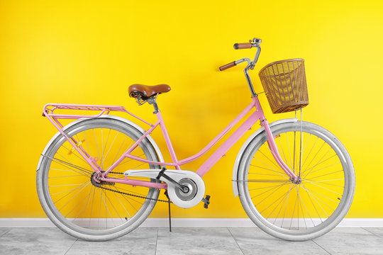 Fototapeta Modern bicycle with wicker basket near color wall