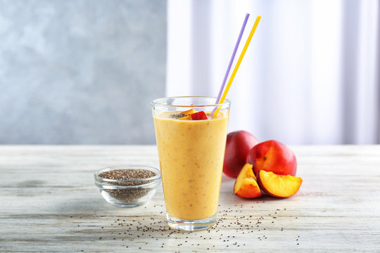 Glass of delicious smoothie with chia seeds and peaches on wooden table
