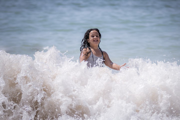Niña morena bañándose en el mar y jugando con las olas.