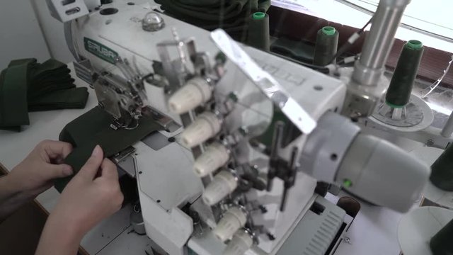 Tailoring of fabric textiles, hands close up focus change to spool threads, dressmaker working at sewing machine, concept clothing factory, high angle view,room interior