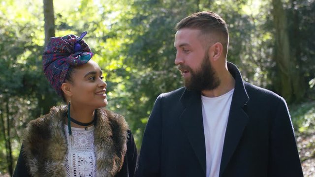 Couple walking in the woods take a moment to share a kiss, in slow motion