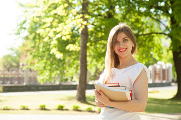 Obraz premium Beautiful smiling student girl in a summer park