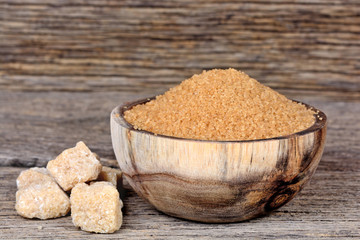 Sugar brown in a bowl with raw sugar on table