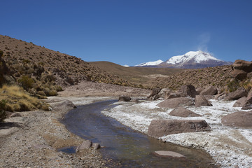 Meandering path of the River Chuba on the Altiplano of northern Chile in Lauca National Park. Snow capped peak of Volcano Guallatiri in the distance.