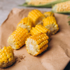 Grilled and raw corns on wooden table