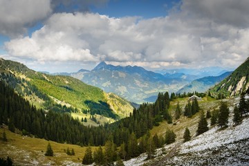 Fototapeta na wymiar Berghaus, Begen mit Wolken und Schnee, Grün, Gelb, Blau, Weiss. 