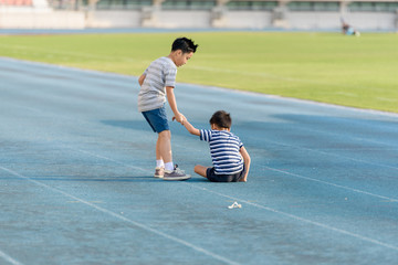 Boy help each other on blue track after fall