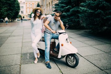 Beautiful young couple sitting on scooter together in the city street