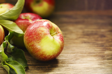 Fresh apples with leaves on wooden background