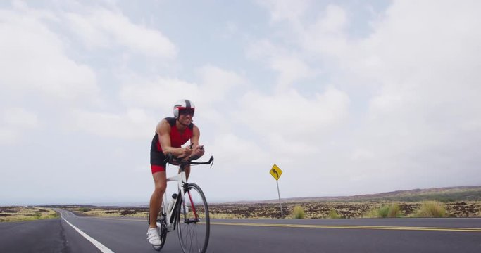 Triathlon biking - male triathlete cycling on triathlon bike. Fit man cyclist on professional triathlon bicycle wearing time trail helmet for ironman race.