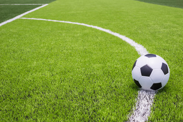 Fototapeta na wymiar Soccer ball on artificial bright and dark green grass at public outdoor football or futsal stadium