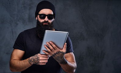A man in a hat and sunglasses holds tablet PC.