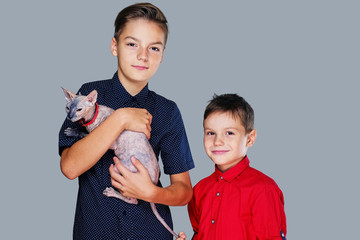 Two teenage boys hold a cat.