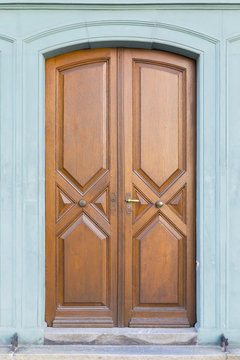 A vintage style carved wooden door with geometric patterns and light green painted wall
