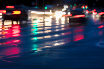 Fototapeta na wymiar blurry image of cars driving on wet road in the city with headlights switched on
