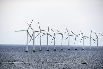 The boat swims by the wind power stations
