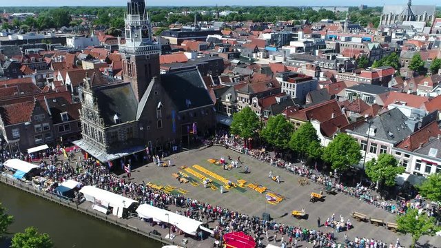 Aerial of traditonal cheese market located at Waagplein Alkmaar showing cheese merchants walking with trays of Alkmaar cheese towards the next buyer this is a popular tourist attraction in Holland 4k