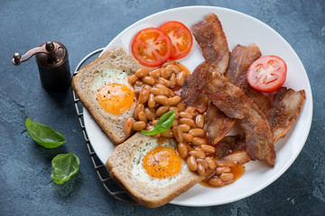 English breakfast with fried bacon, eggs in the basket and beans, studio shot