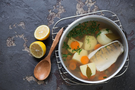 Above view of fish soup with sudak in a kettle on a brown stone background