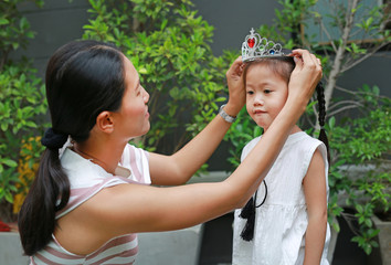 Fototapeta premium Mother wearing crown on head of little girl in the garden.