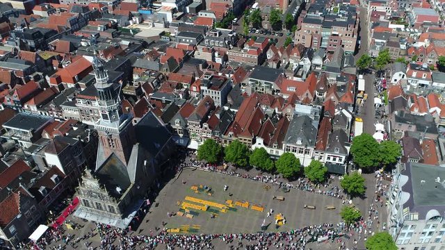 Aerial top down view of traditonal cheese market at Waagplein Alkmaar showing cheese merchants walking with trays of Alkmaar cheese towards next buyer this is popular tourist attraction in Netherlands
