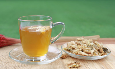 Chrysanthemum juice in glass cup and dried Chrysanthemum flower on wood background.