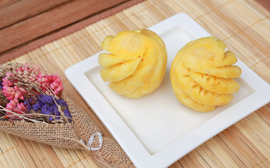 Pineapple fruit in ceramic plate on wooden table.