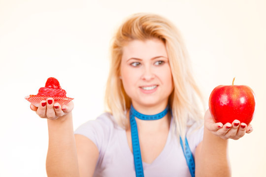 Woman choosing between apple and sweet cupcake